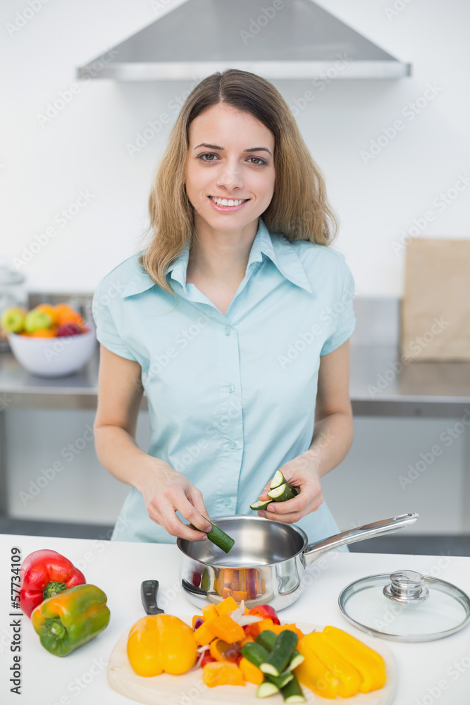 Sweet smiling woman cutting vegetables standing in kitchen