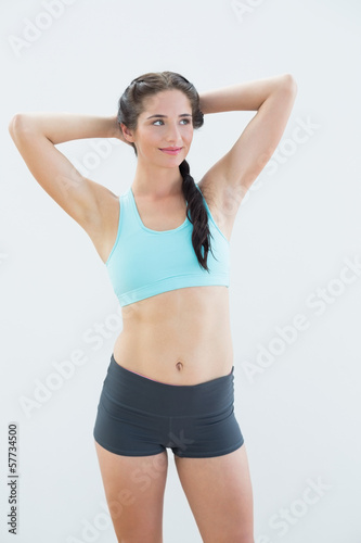 Fit young woman standing with hands behind head