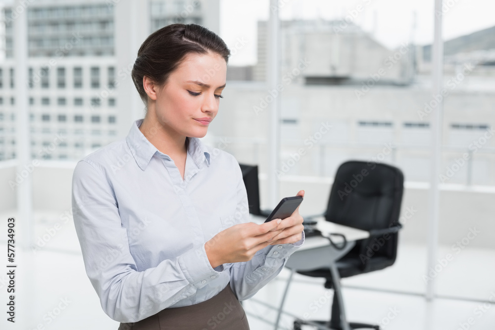 Serious businesswoman reading text message in office