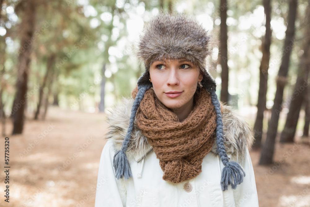 Woman wearing fur hat with woolen scarf and jacket in woods