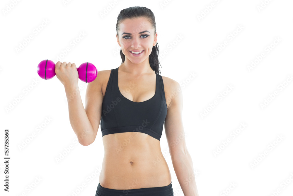 Joyful active woman training with a dumbbell smiling at camera Joyful active woman training with a dumbbell smiling at camera
