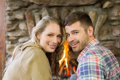 Smiling young couple in front of lit fireplace © lightwavemedia