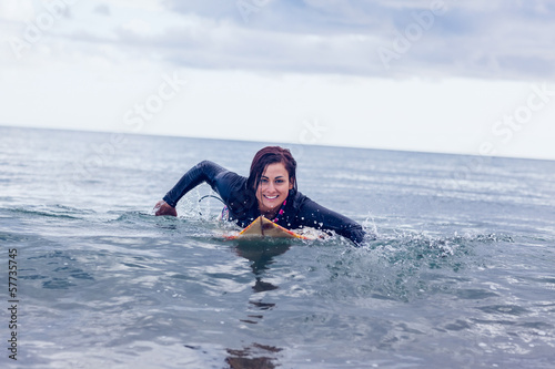 Smiling woman swimming over surfboard in water © WavebreakMediaMicro
