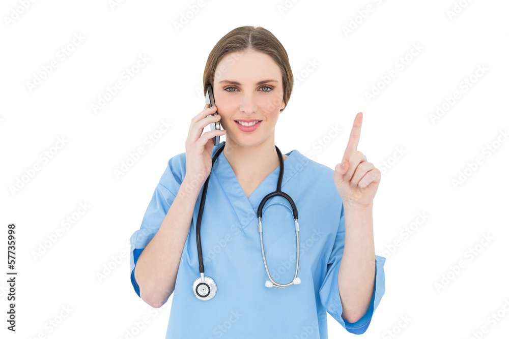 Pretty woman doctor phoning and pointing with her finger Pretty woman doctor phoning and pointing with her finger