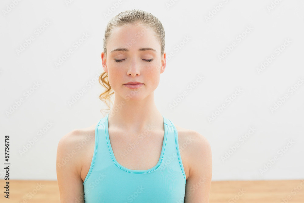 Calm slim blonde sitting on floor with closed eyes