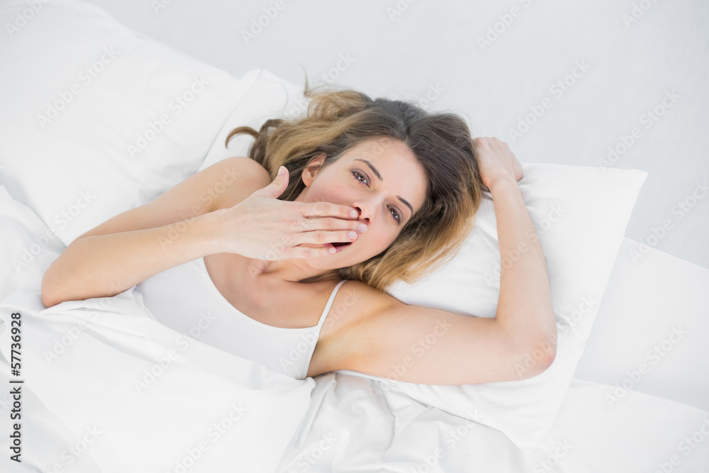 Gorgeous tired woman yawning lying on her bed Gorgeous tired woman yawning lying on her bed