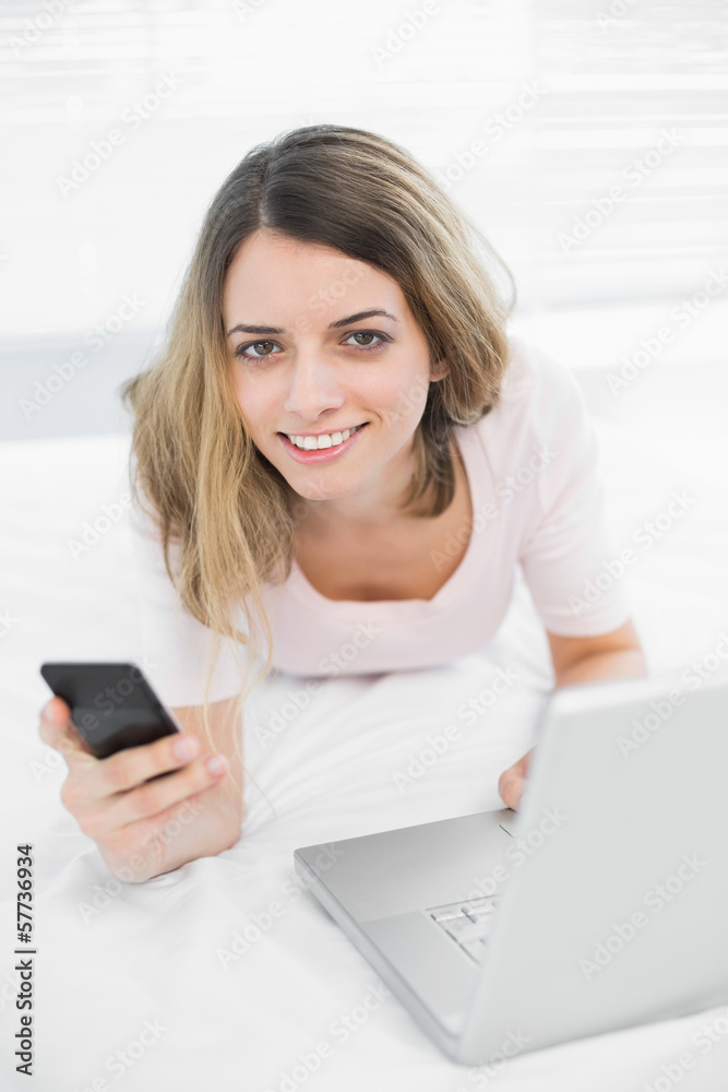 Cute smiling woman holding her smartphone looking at camera Cute smiling woman holding her smartphone looking at camera