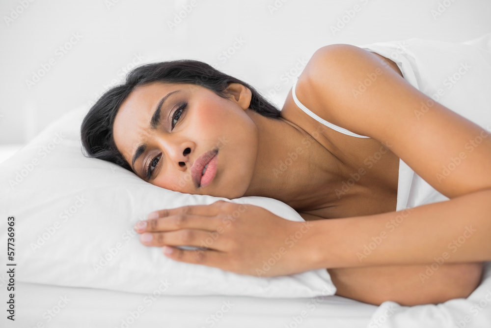 Young attractive woman lying on her bed wrinkling her brow Young attractive woman lying on her bed wrinkling her brow