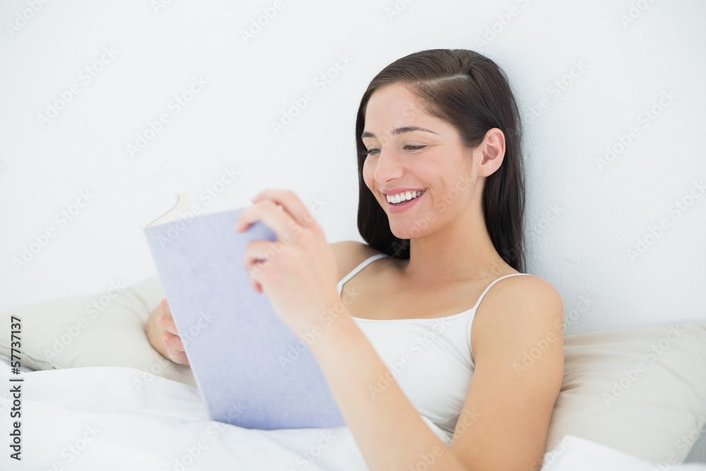 Smiling woman reading a book in bed Smiling woman reading a book in bed