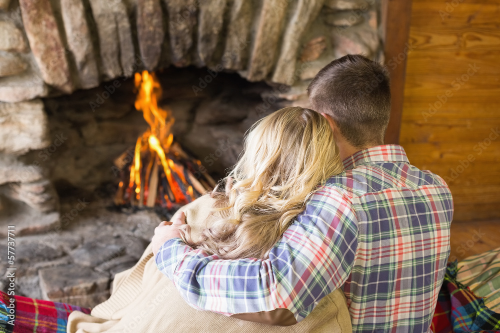Romantic couple sitting in front of lit fireplace Romantic couple sitting in front of lit fireplace