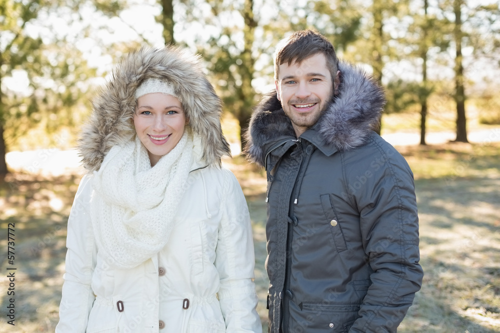 Smiling couple in fur hood jackets in the woods Smiling couple in fur hood jackets in the woods