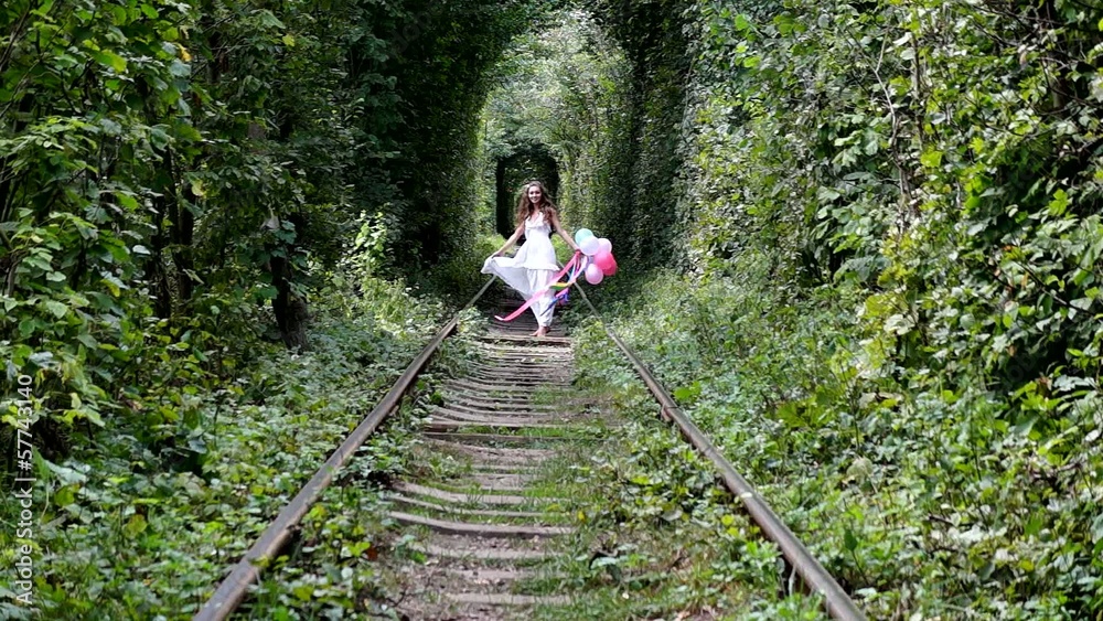 Girl walking along the forest railway. In hands colored balls. Girl walking along the forest railway. In hands colored balls.