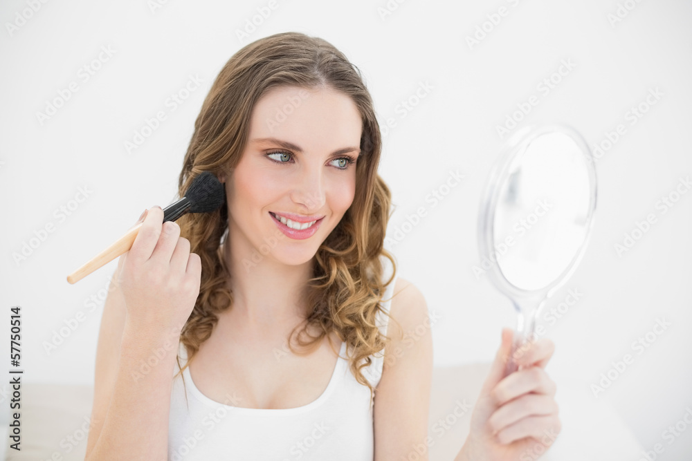 Smiling woman putting powder on her cheeks Smiling woman putting powder on her cheeks