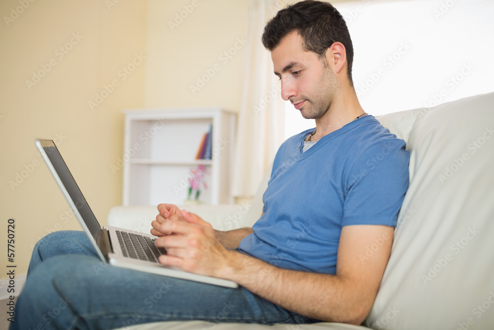 Casual calm man sitting on couch using looking at laptop Casual calm man sitting on couch using looking at laptop