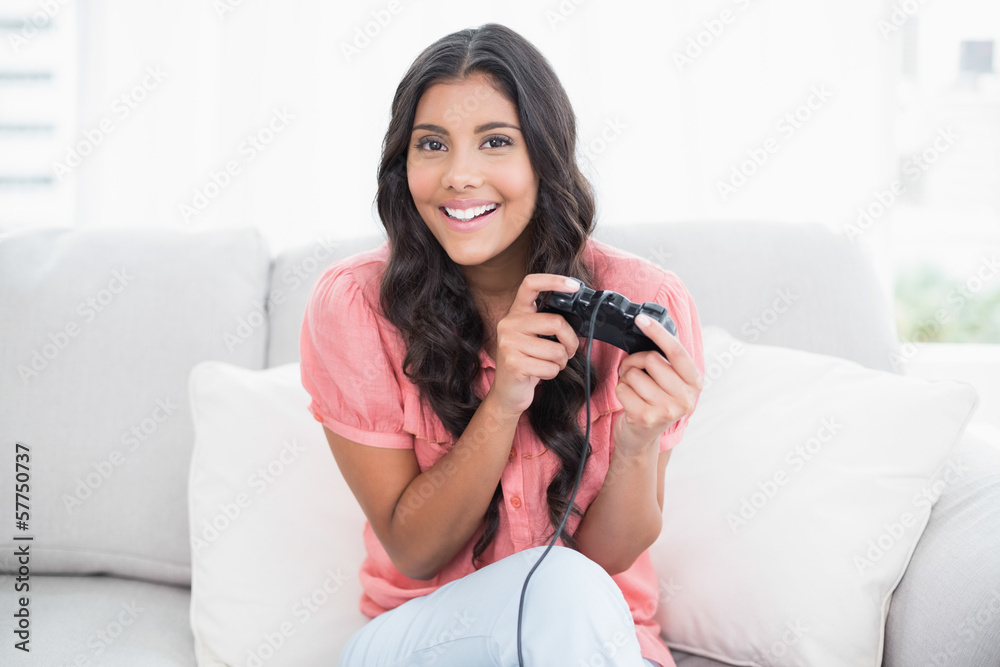 Happy cute brunette sitting on couch holding controller Happy cute brunette sitting on couch holding controller