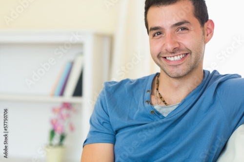 Casual smiling man relaxing on couch looking at camera