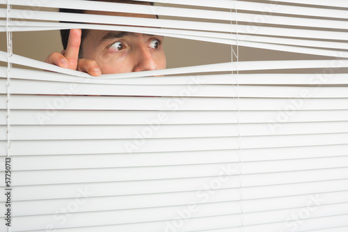 Scared male eyes spying through roller blind