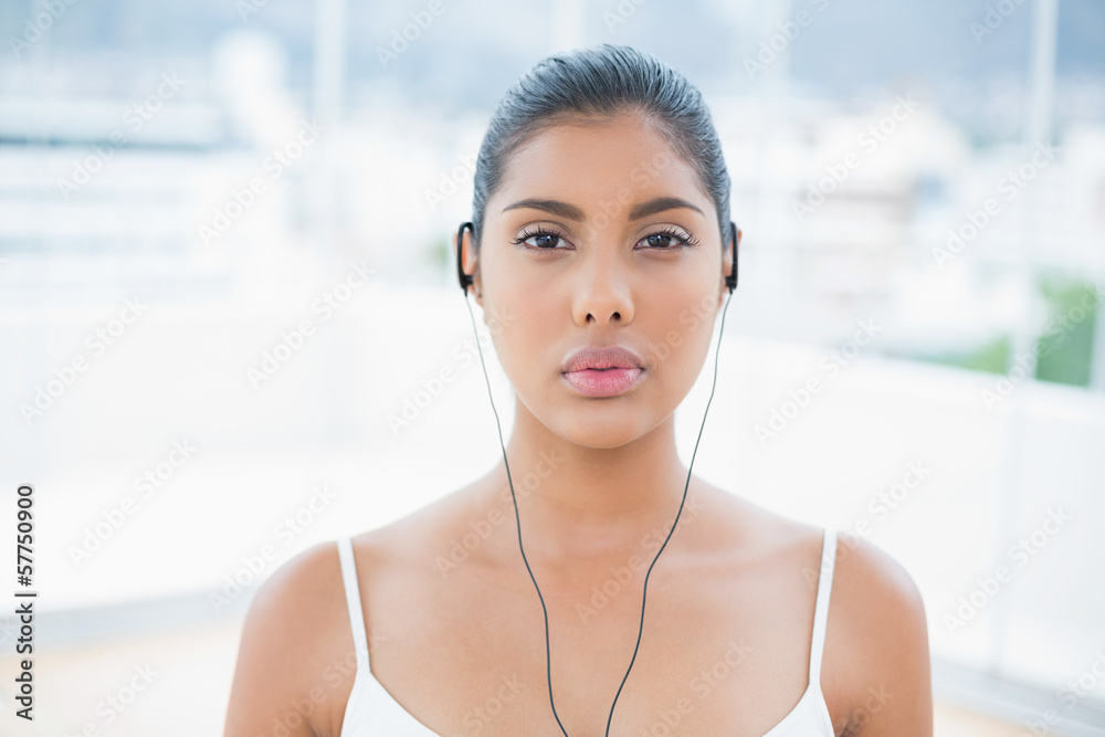 Unsmiling toned brunette listening to music