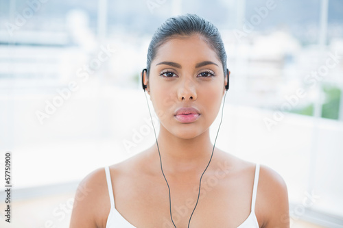 Unsmiling toned brunette listening to music