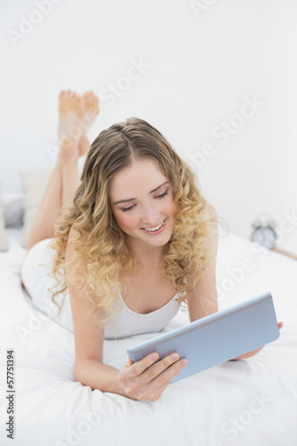 Pretty lucky blonde lying on bed using tablet