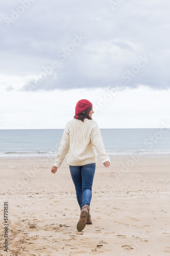 Rear view of a woman in stylish warm wear on beach