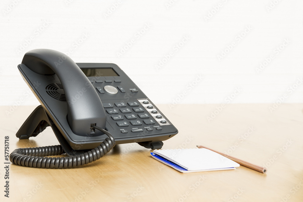phone on desk with notepad on wooden desk phone on desk with notepad on wooden desk