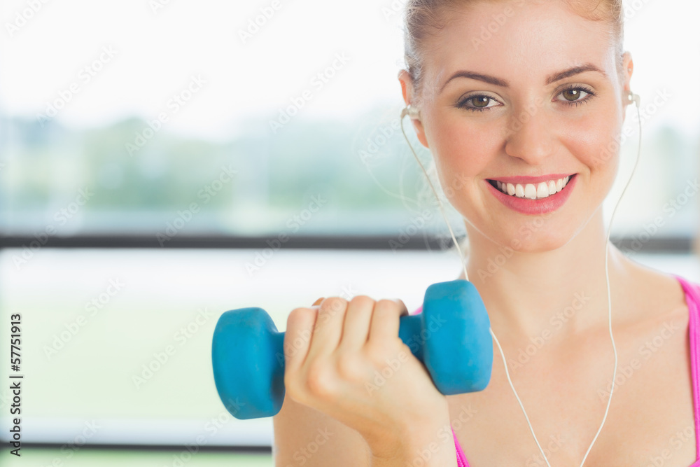 Fit woman exercising with dumbbells in fitness studio