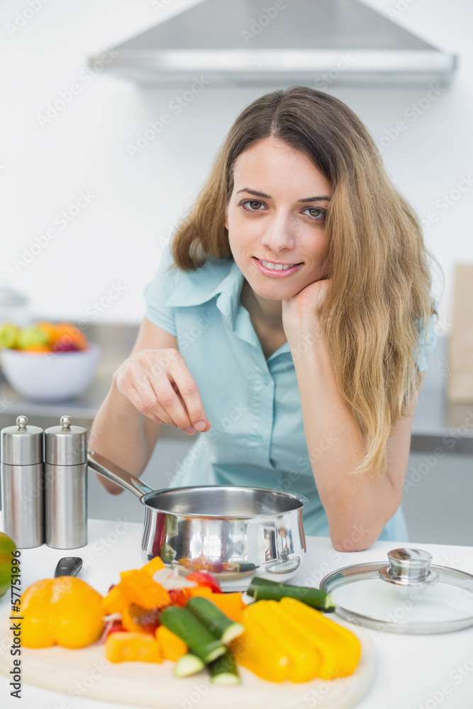 Young cute woman cooking while smiling at camera Young cute woman cooking while smiling at camera