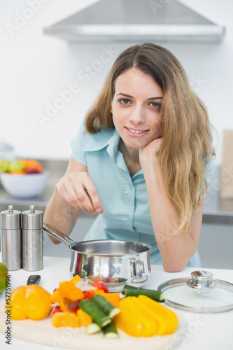 Young cute woman cooking while smiling at camera