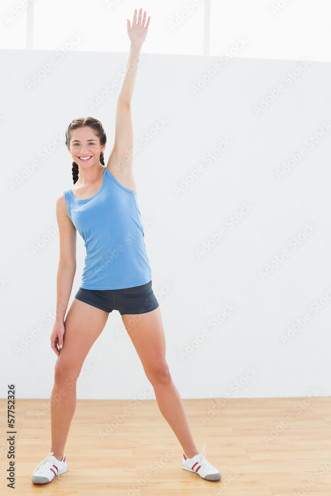 Full length of a woman stretching hand in fitness center