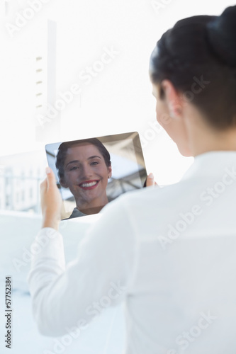 Business woman looking at her reflection in tablet PC