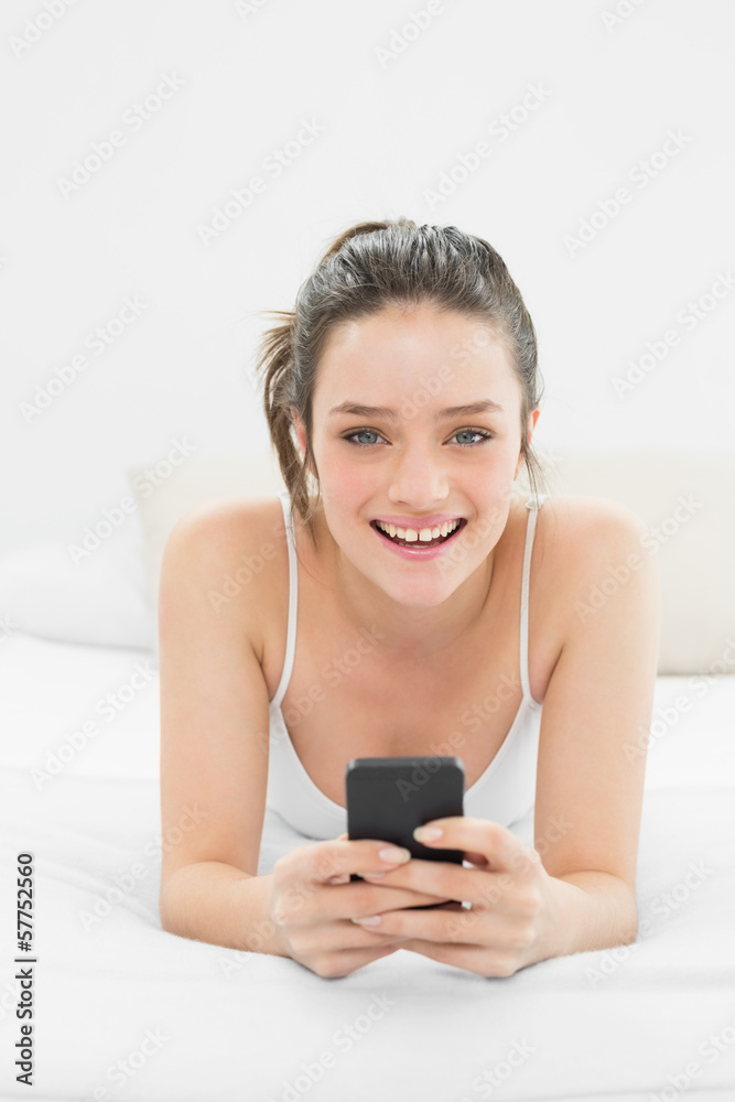 Happy casual woman with mobile phone in bed Happy casual woman with mobile phone in bed