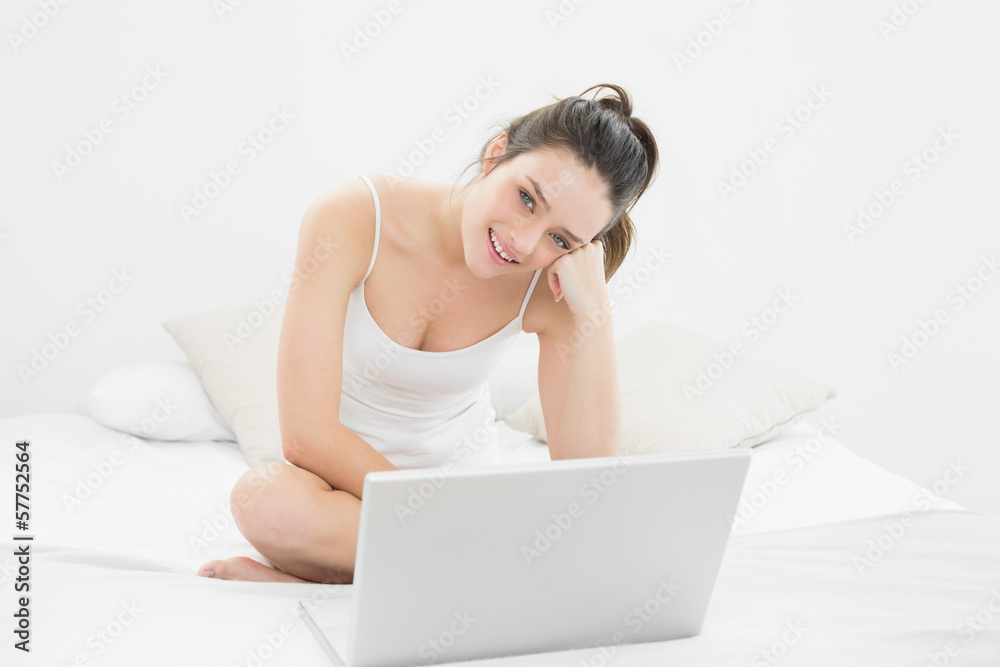 Smiling casual woman with laptop sitting on bed Smiling casual woman with laptop sitting on bed
