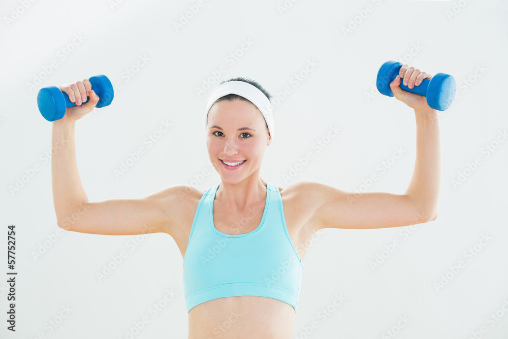Fit smiling woman exercising with dumbbells Fit smiling woman exercising with dumbbells
