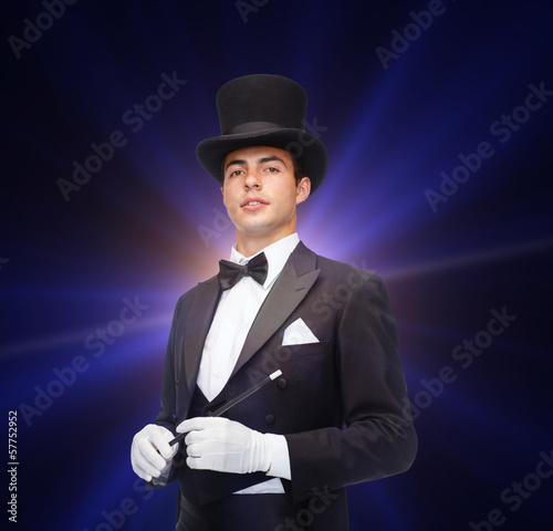 magician in top hat with magic wand showing trick