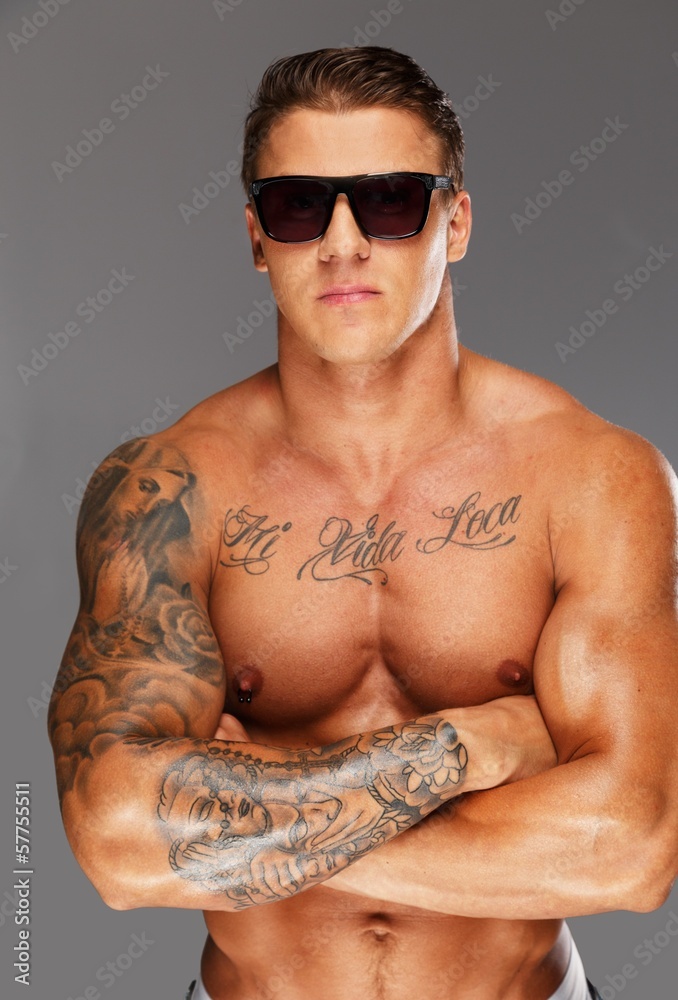 Fototapeta premium Handsome man in sunglasses with muscular tattooed torso