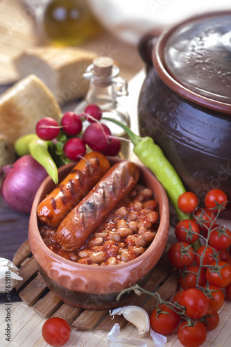 plate of baked beans and sausage with vegetables on the table