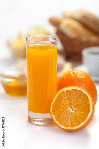 orange juice  with breakfast and coffe in the background