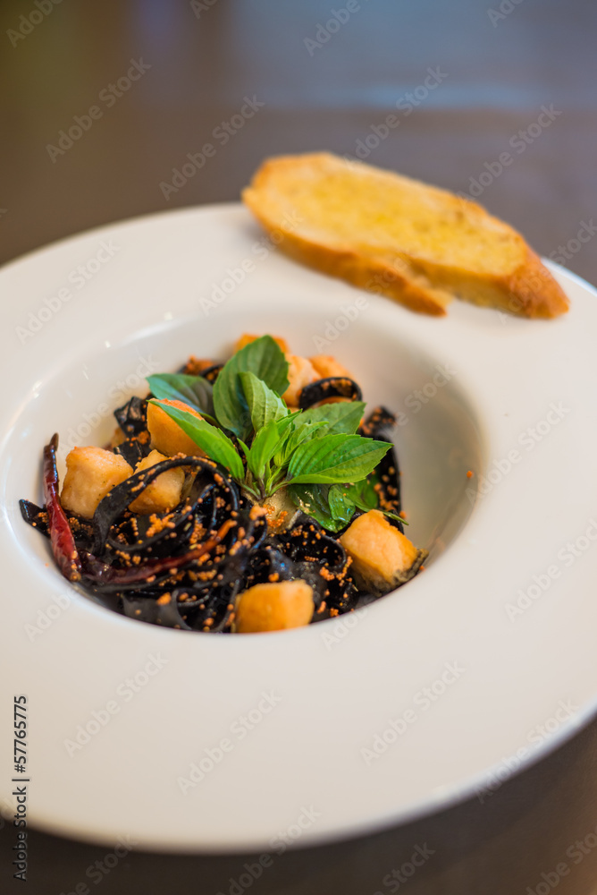 Cooked black pasta noodle served with buttered bread