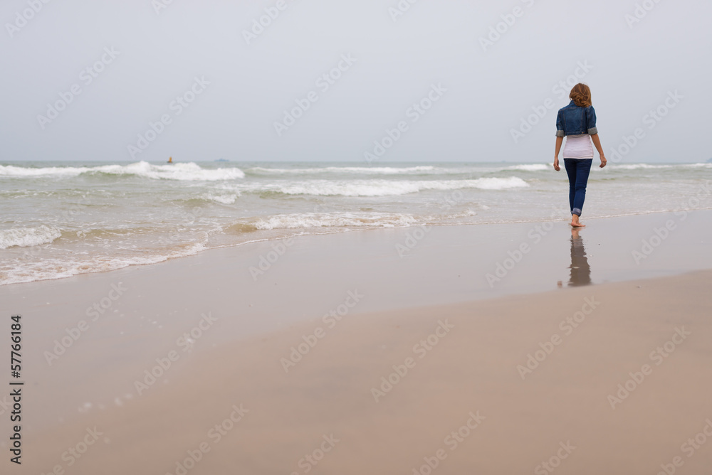 Young woman walking on the beach alone