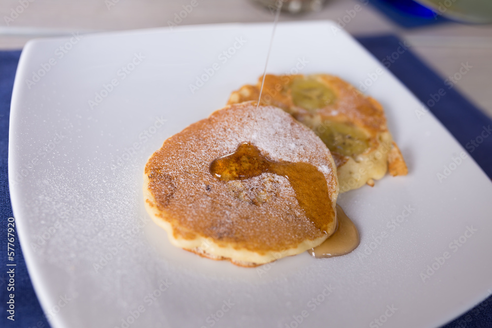 honey pouring on pancake set on white dish as breakfast