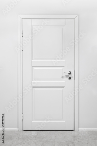 Classical closed wooden door in white office wall