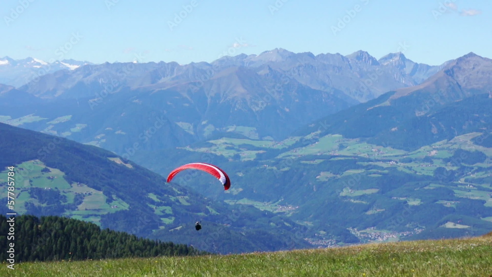 Colorful hang glider in sky over mountains, Kronplatz, Italy Colorful hang glider in sky over mountains, Kronplatz, Italy