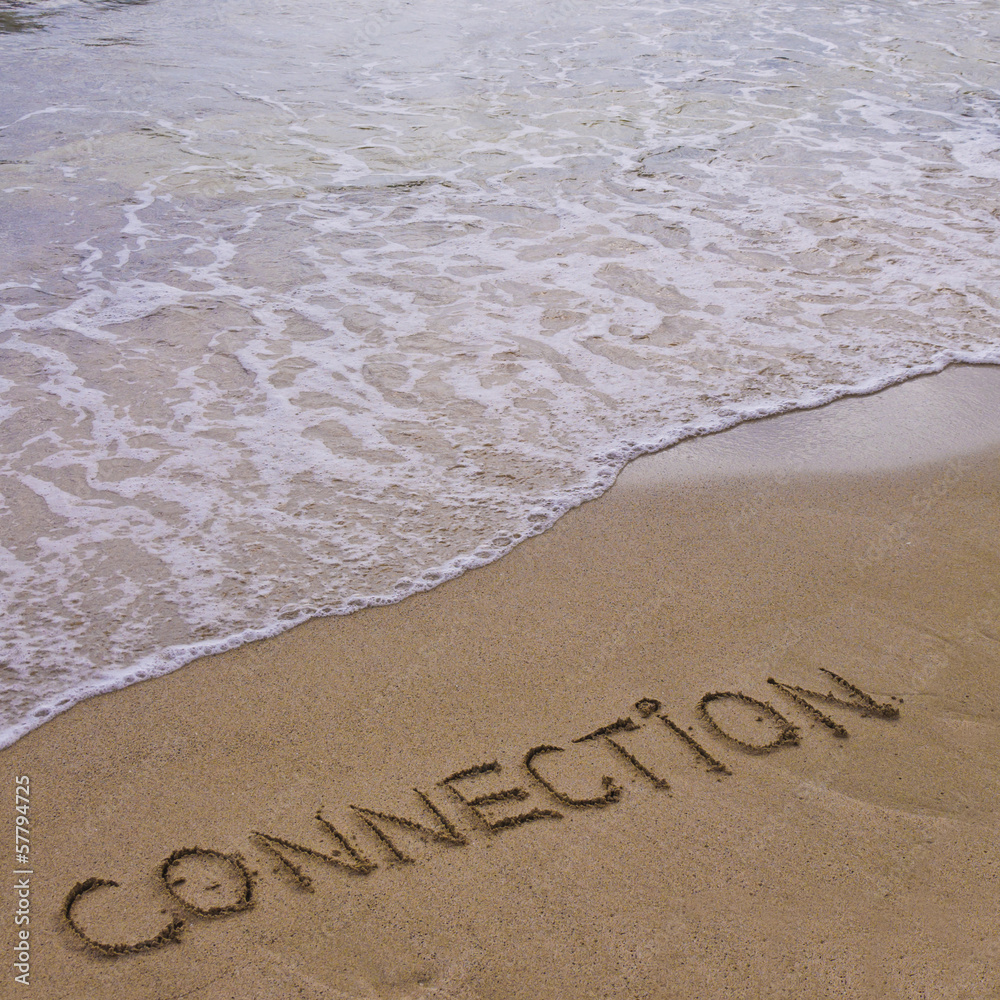 Fototapeta premium Connection word written on sand, with waves in background