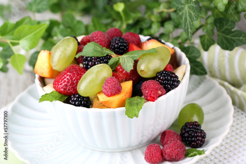 Fruit salad in bowl  on wooden table  on bright background