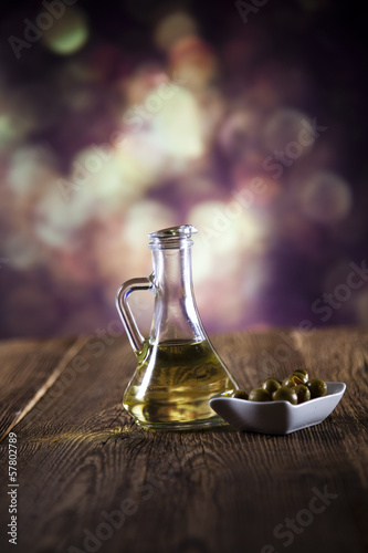 Flagon with olive oil, fresh olives on a plate