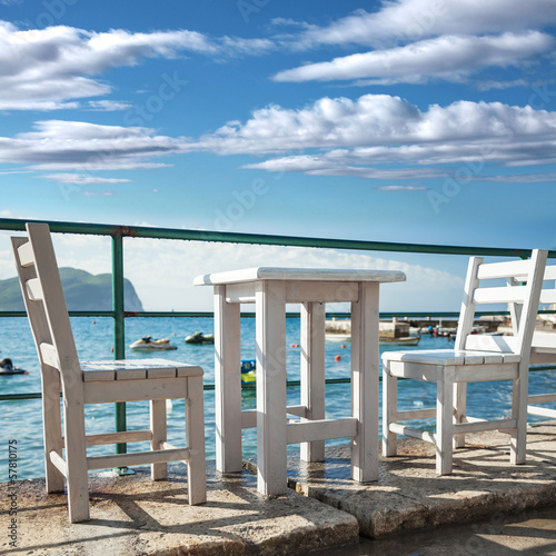 White wooden chairs and table stand on sea coast © evannovostro