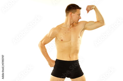 Young athletic man shows biceps muscle and look on arm.