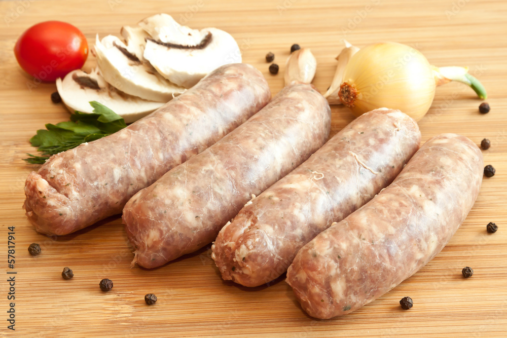 Uncooked sausages with vegetables on the chopping board Uncooked sausages with vegetables on the chopping board