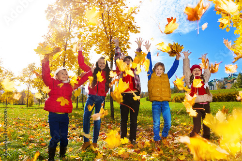Group of kids throw autumn leaves